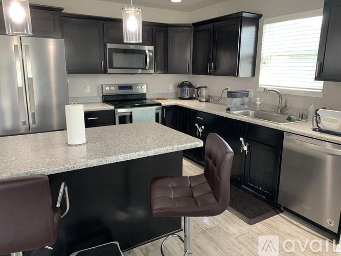 A kitchen with a granite countertop and a black chair.