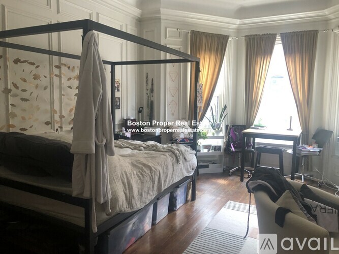 A bedroom with a four poster bed and a desk with a chair.