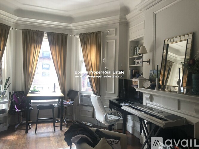 A room with a piano, a desk with a chair, and a window with curtains.