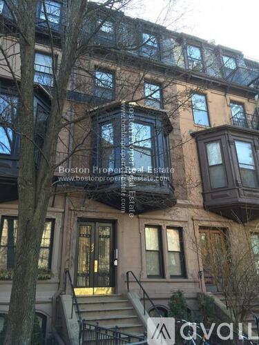 A building with a balcony and a tree in front of it.