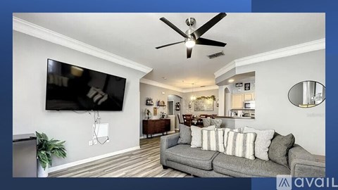 A living room with a grey couch and a flat screen TV mounted on the wall.
