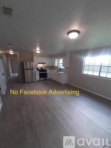 A kitchen area with a refrigerator, sink, and cabinets.