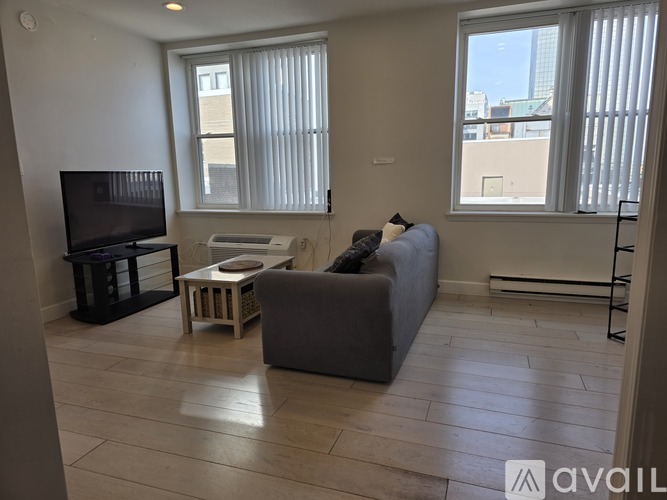 A living room with a grey couch, a wooden table, and a television.