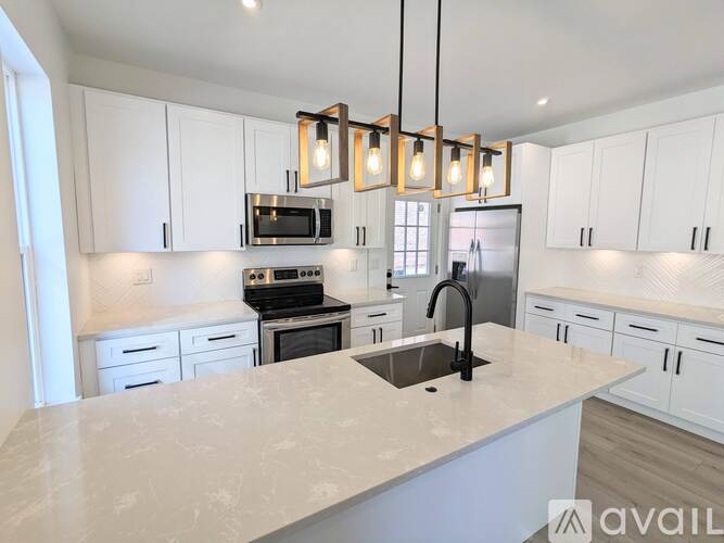 A kitchen with white cabinets and a marble countertop.