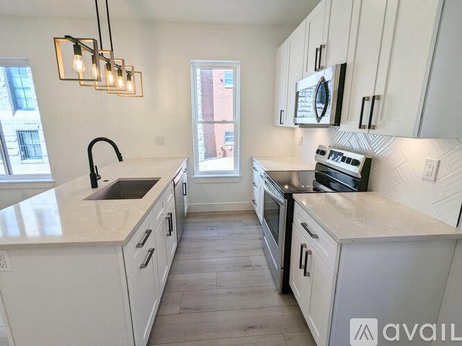 A kitchen with white cabinets and a marble countertop.