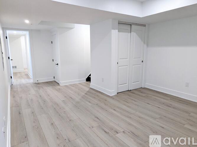 A spacious room with wood flooring and white walls.