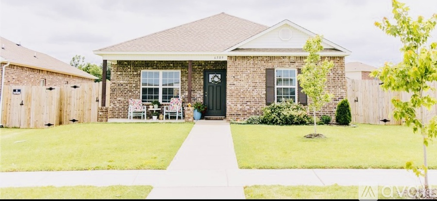 A brick house with a black front door and a small front yard.