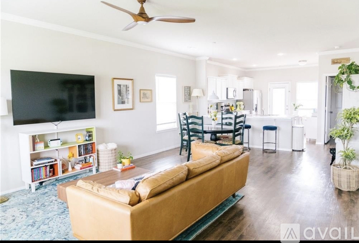A living room with a brown couch and a television on the wall.