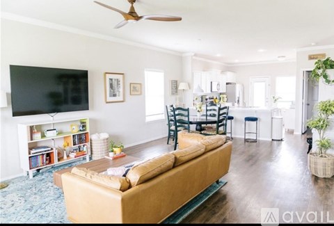 A living room with a brown couch and a television on the wall.