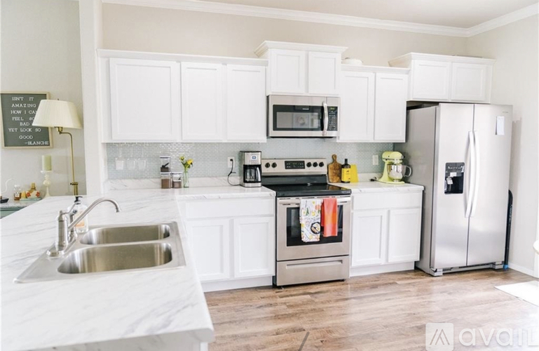 A kitchen with white cabinets and a wooden floor.