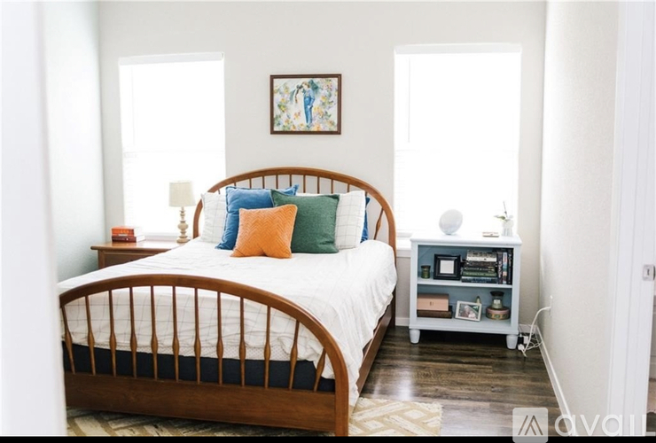 A bedroom with a bed, nightstand, and a painting on the wall.