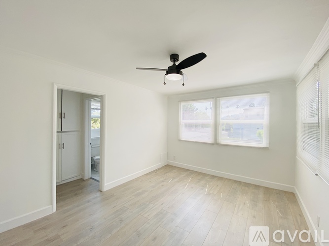 A room with a ceiling fan and a door leading to another room.
