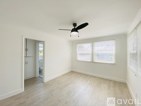 A room with a ceiling fan and a door leading to another room.