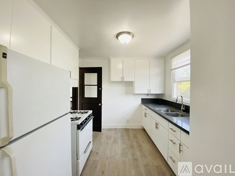 A kitchen with white cabinets and a black door.