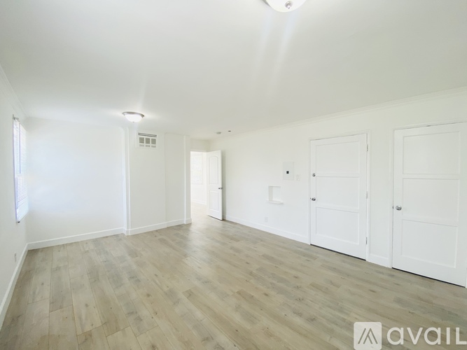 A spacious room with wooden flooring and white walls.