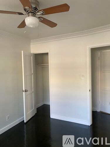 A spacious room with wooden flooring and white walls.