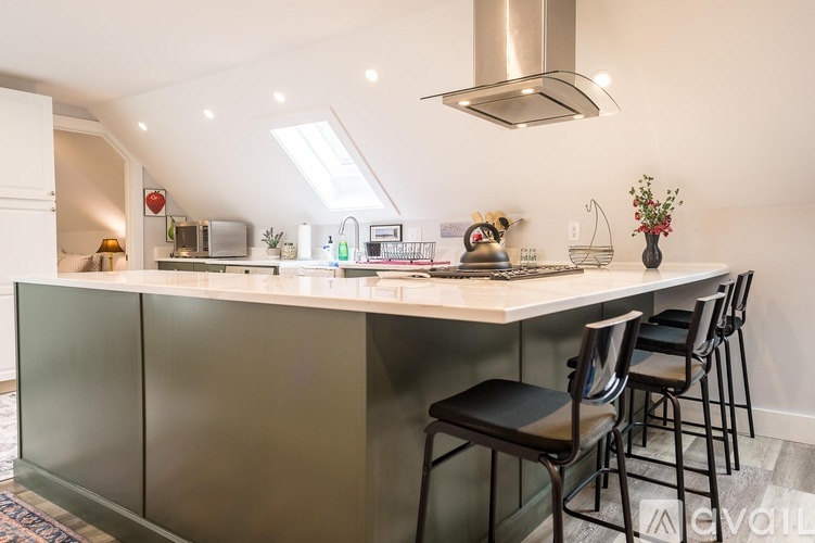 A kitchen with a white countertop and black chairs.