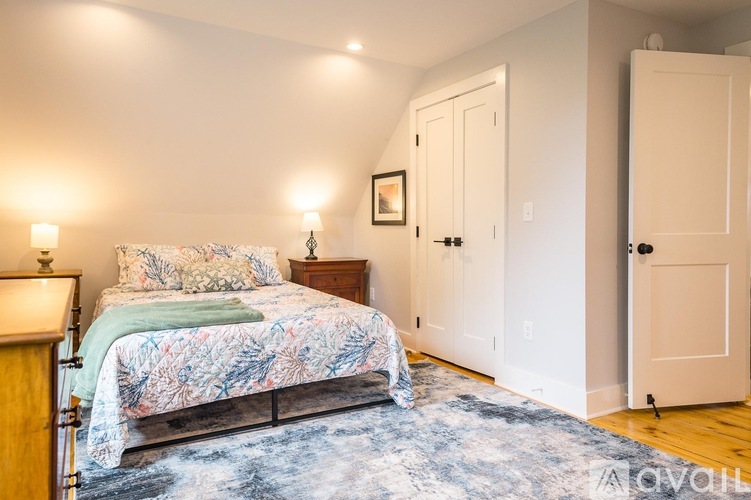 A bedroom with a bed, two lamps, and a painting on the wall.