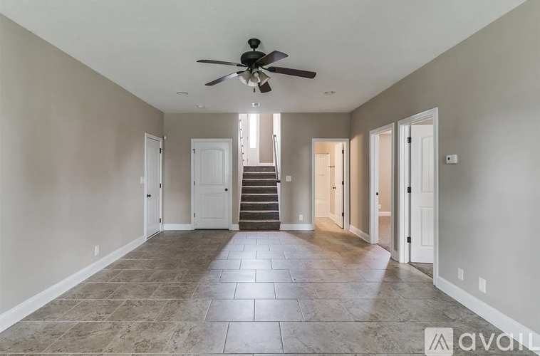A spacious room with a fan and tiled flooring.