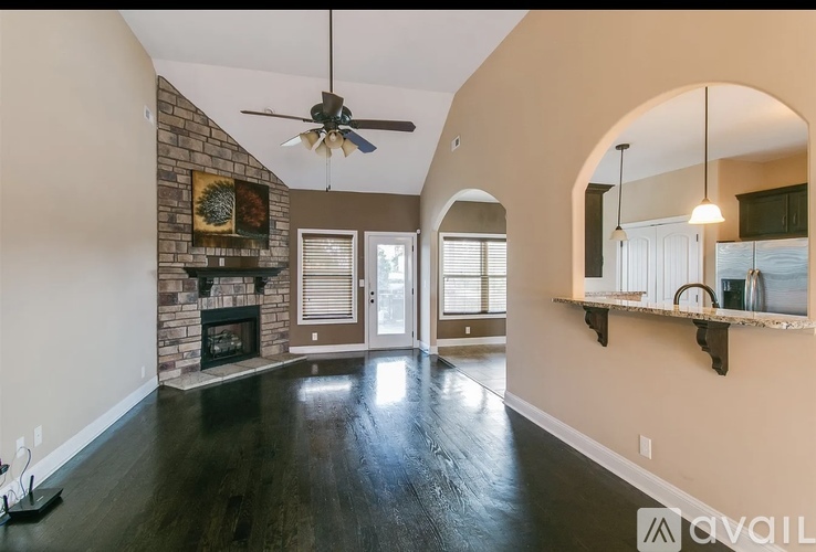 A spacious living room with a fireplace and a ceiling fan.