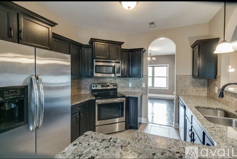A kitchen with a stainless steel refrigerator and black cabinets.