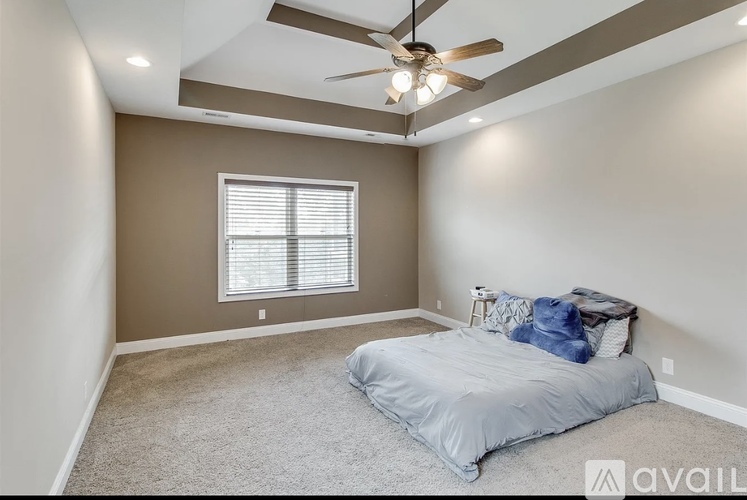 A bedroom with a bed, ceiling fan, and carpeted floor.
