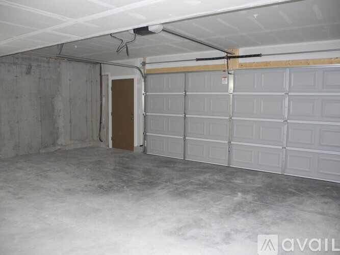 A spacious garage with a white ceiling and a brown door.