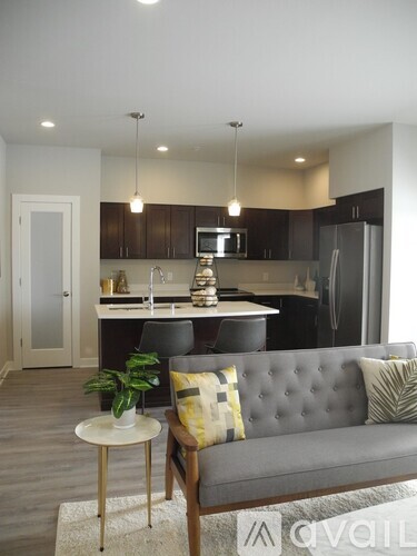 A modern kitchen with a grey couch and a small table with a plant on it.