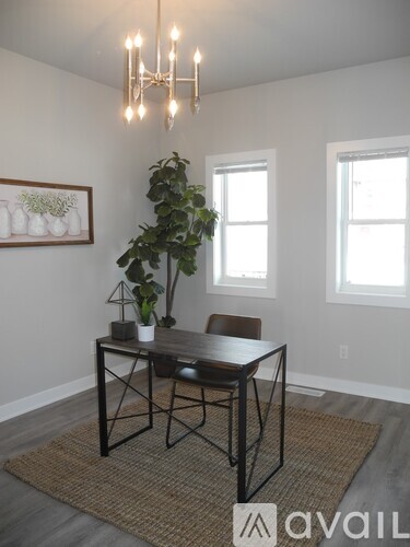 A dining room with a table and chairs and a potted plant.