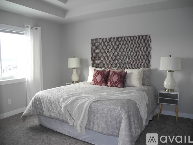 A bedroom with a large bed and two lamps.