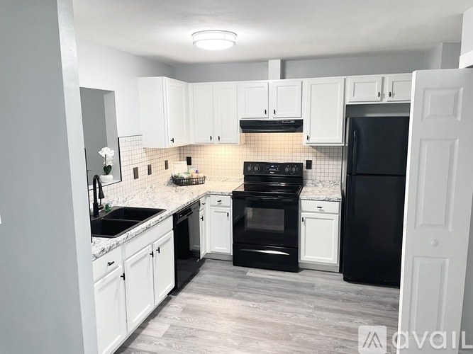 A kitchen with black appliances and white cabinets.