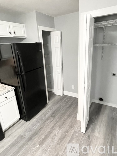 A black refrigerator in a kitchen with white cabinets and a white door.