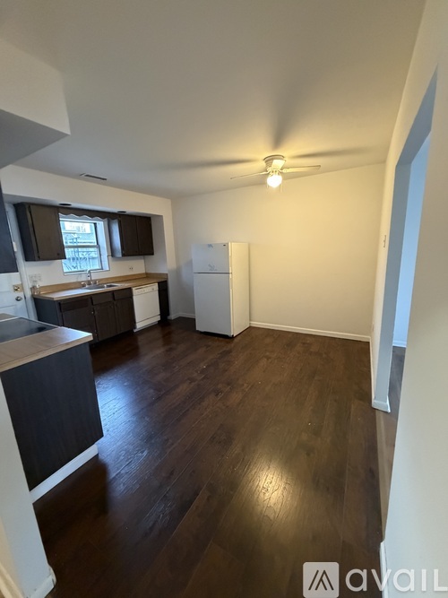 A kitchen with dark wood floors and white appliances.