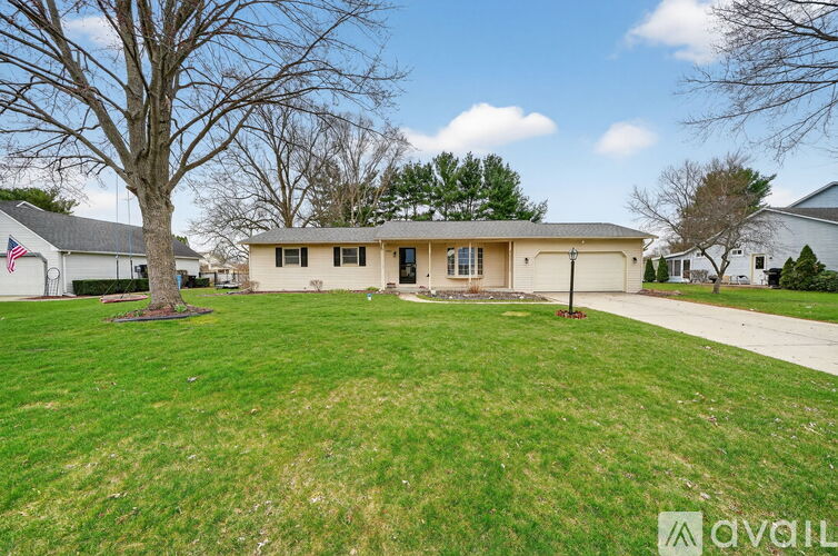 A house with a lawn and a tree in front of it.