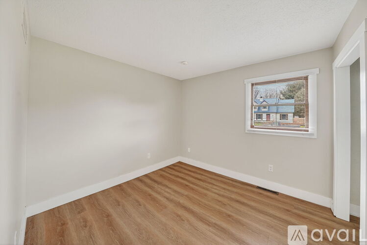 A room with wooden flooring and a window showing a view of a building outside.