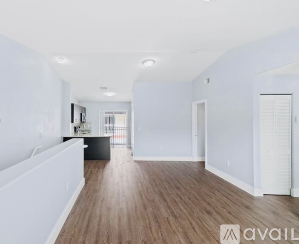 A spacious room with wooden flooring and white walls.