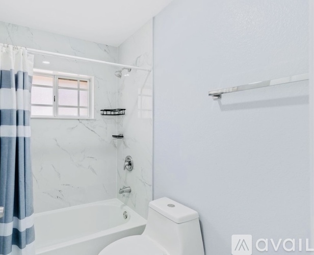 A white bathroom with a striped shower curtain.