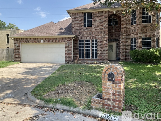 A brick house with a white garage door and a brick pillar with a mailbox on it.