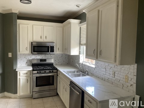 A kitchen with white cabinets and a marble countertop.