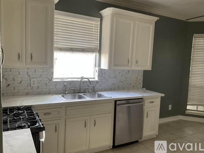 A kitchen with white cabinets and a marble backsplash.