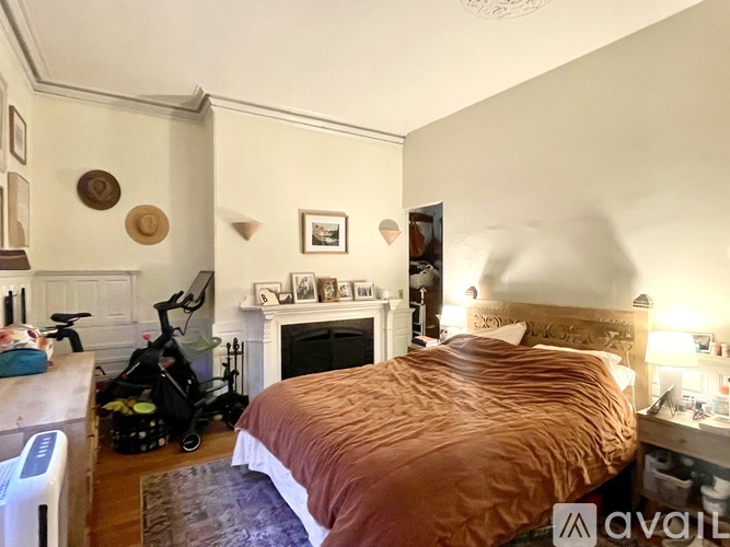 A bedroom with a bed, a fireplace, and a baby stroller.