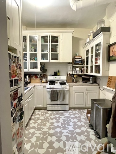 A kitchen with white cabinets and a patterned floor.