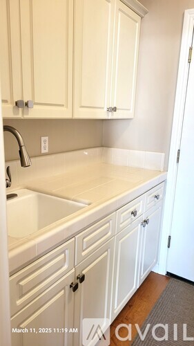 A kitchen with white cabinets and a white sink.