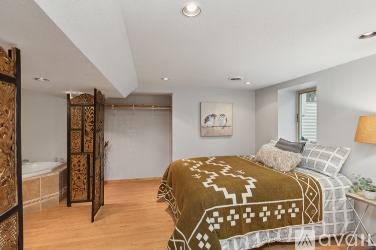 A bedroom with a bed covered in a patterned blanket and a wooden cabinet.