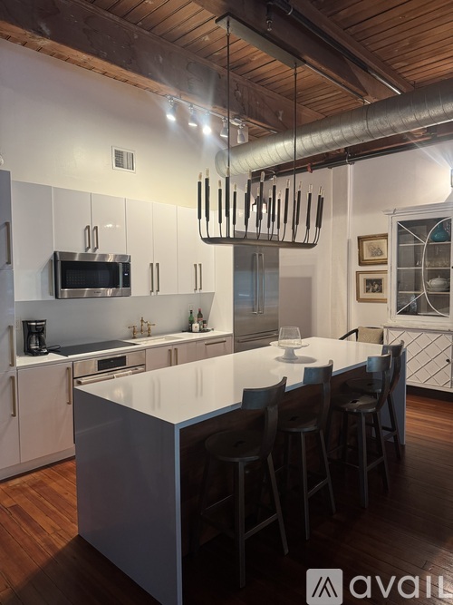 A modern kitchen with a white island and dark wood floors.