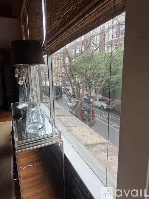 A lamp on a table by a window with a view of the street outside.