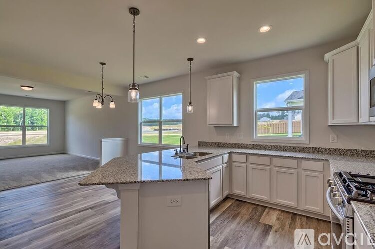 A modern kitchen with a large island and pendant lights.