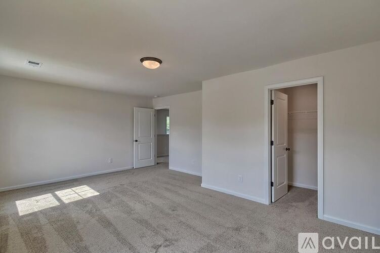 A room with a carpeted floor and two doors, one of which is open.