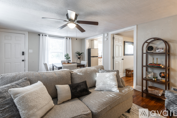 A living room with a grey couch and a ceiling fan.