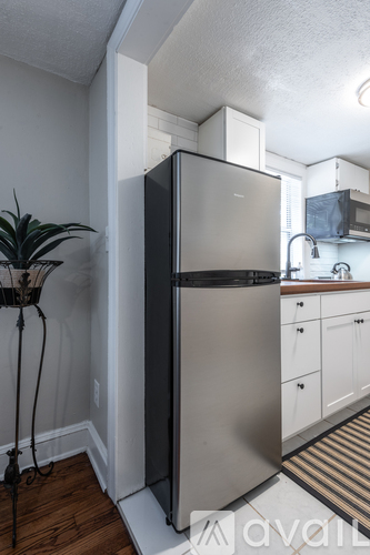 A black refrigerator in a kitchen with white cabinets.